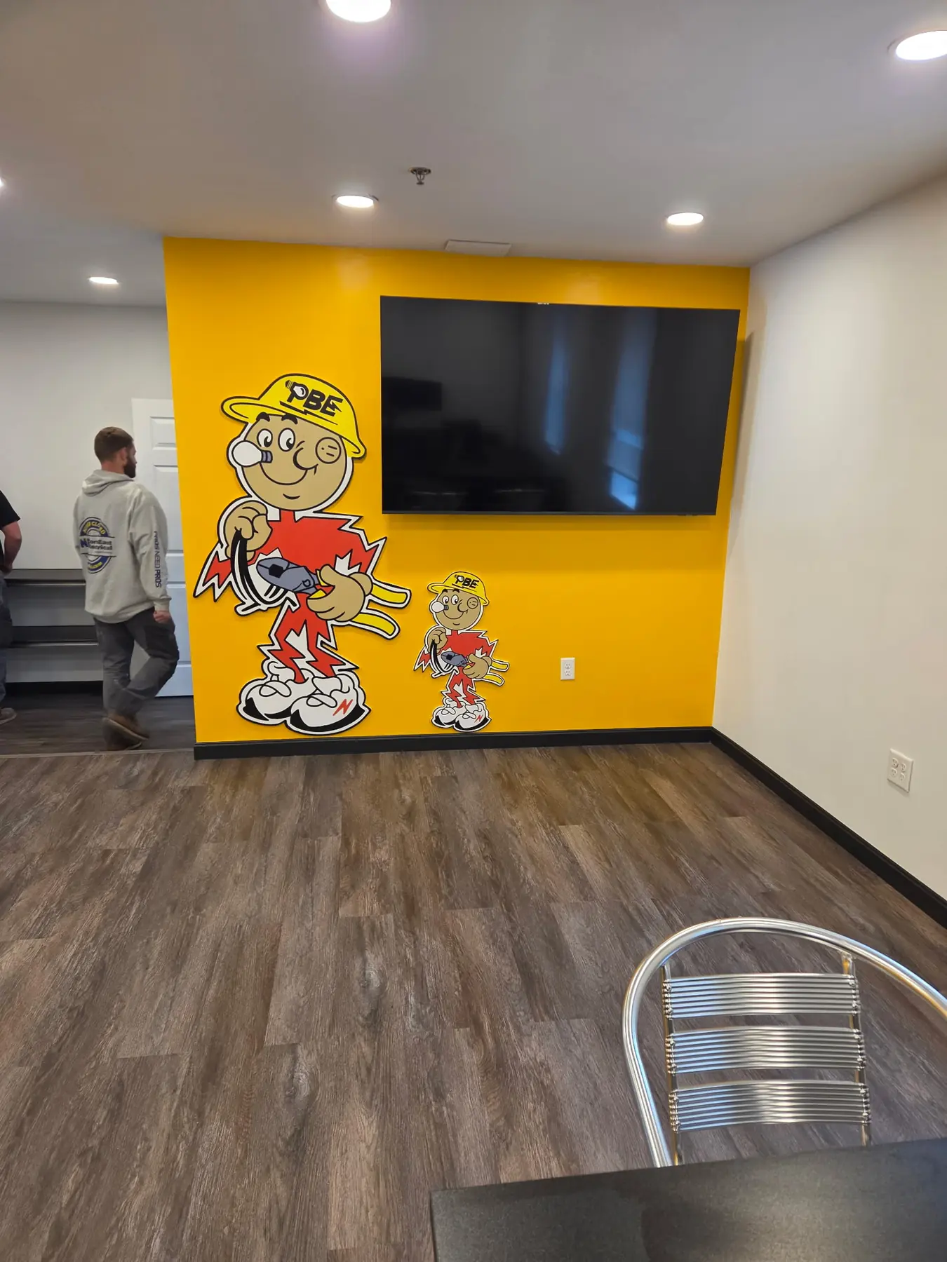 Gráficos grandes y pequeños de la mascota de PBE cortados al contorno e instalados en una pared de oficina